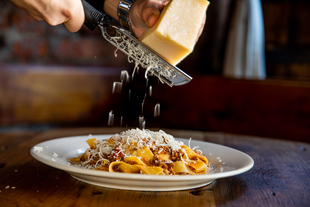 Pasta bolognese with extra cheese being grated on top.