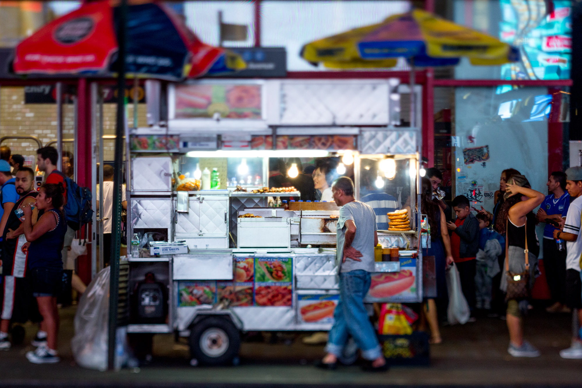 A hardworking man looks tired behind a food cart